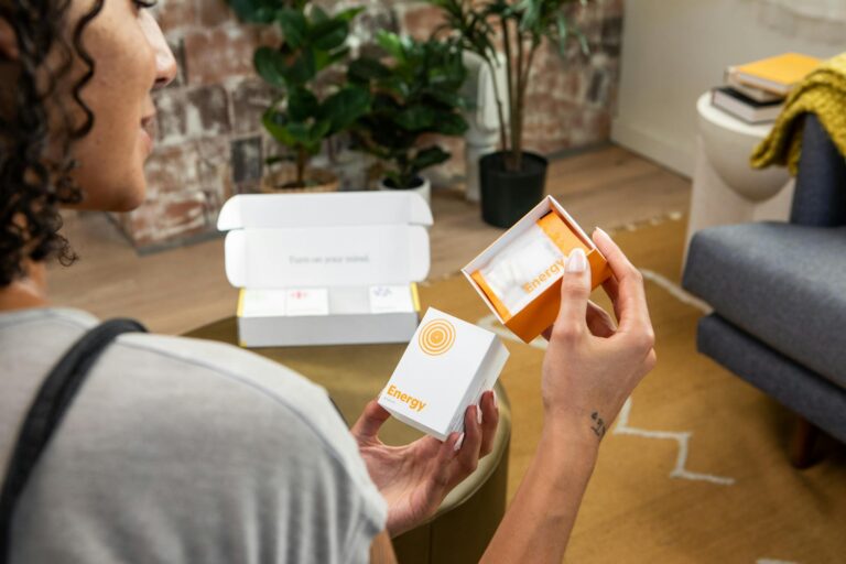 A woman holds energy supplements in a stylish living space, promoting wellness and lifestyle benefits.