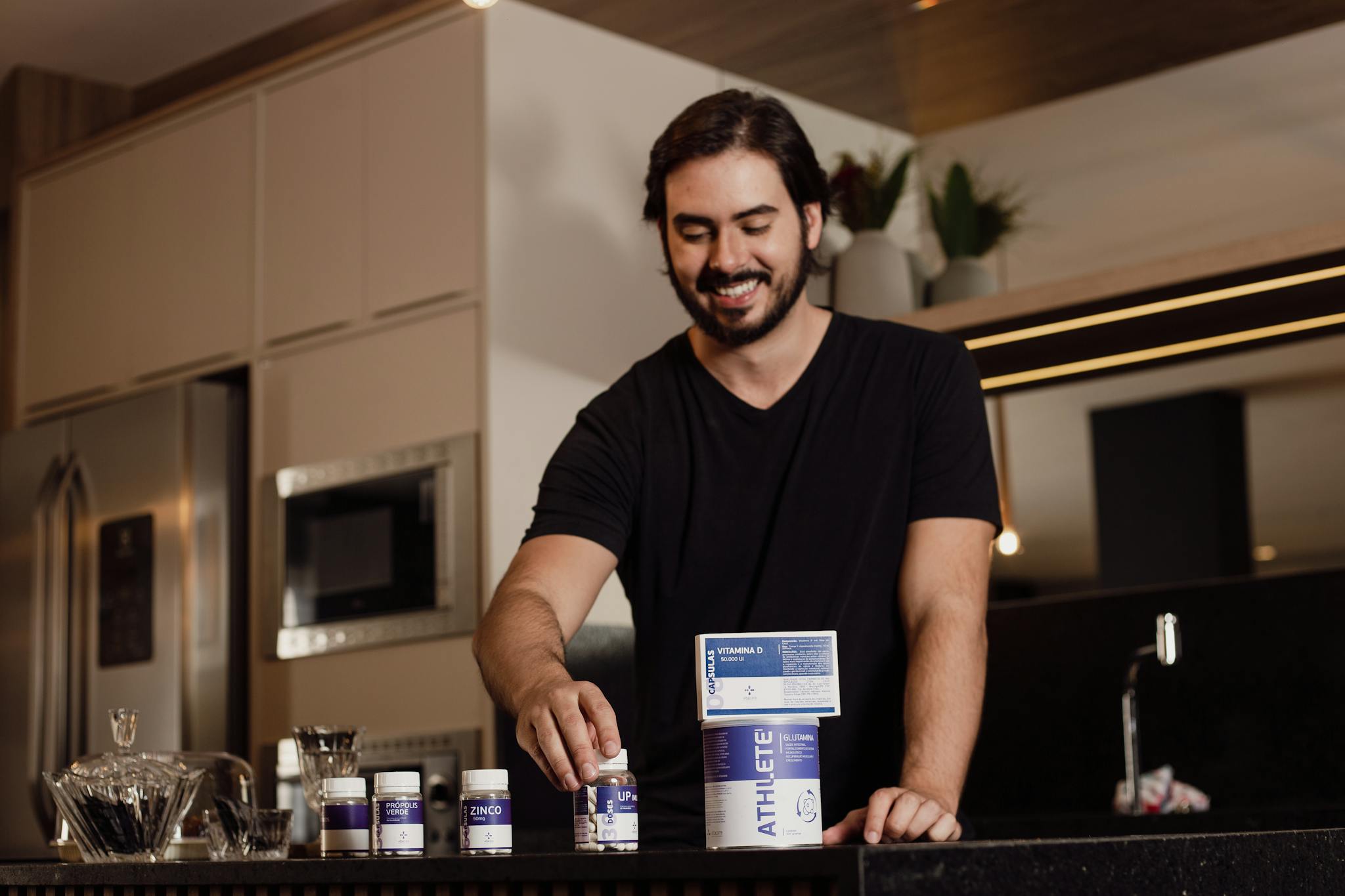Smiling man arranging vitamin supplements on kitchen counter.